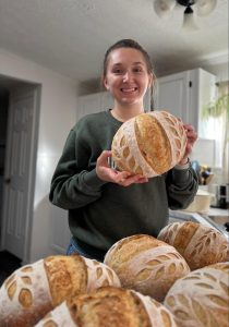 sourdough student holding her bread 
